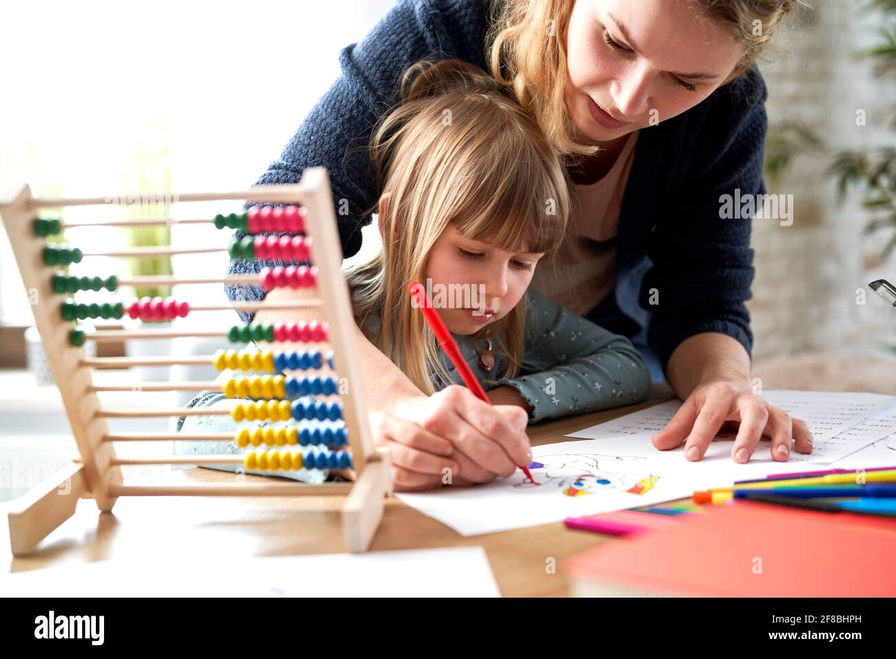 Madre ayudando a la hija pequeña con la tarea Foto de stock