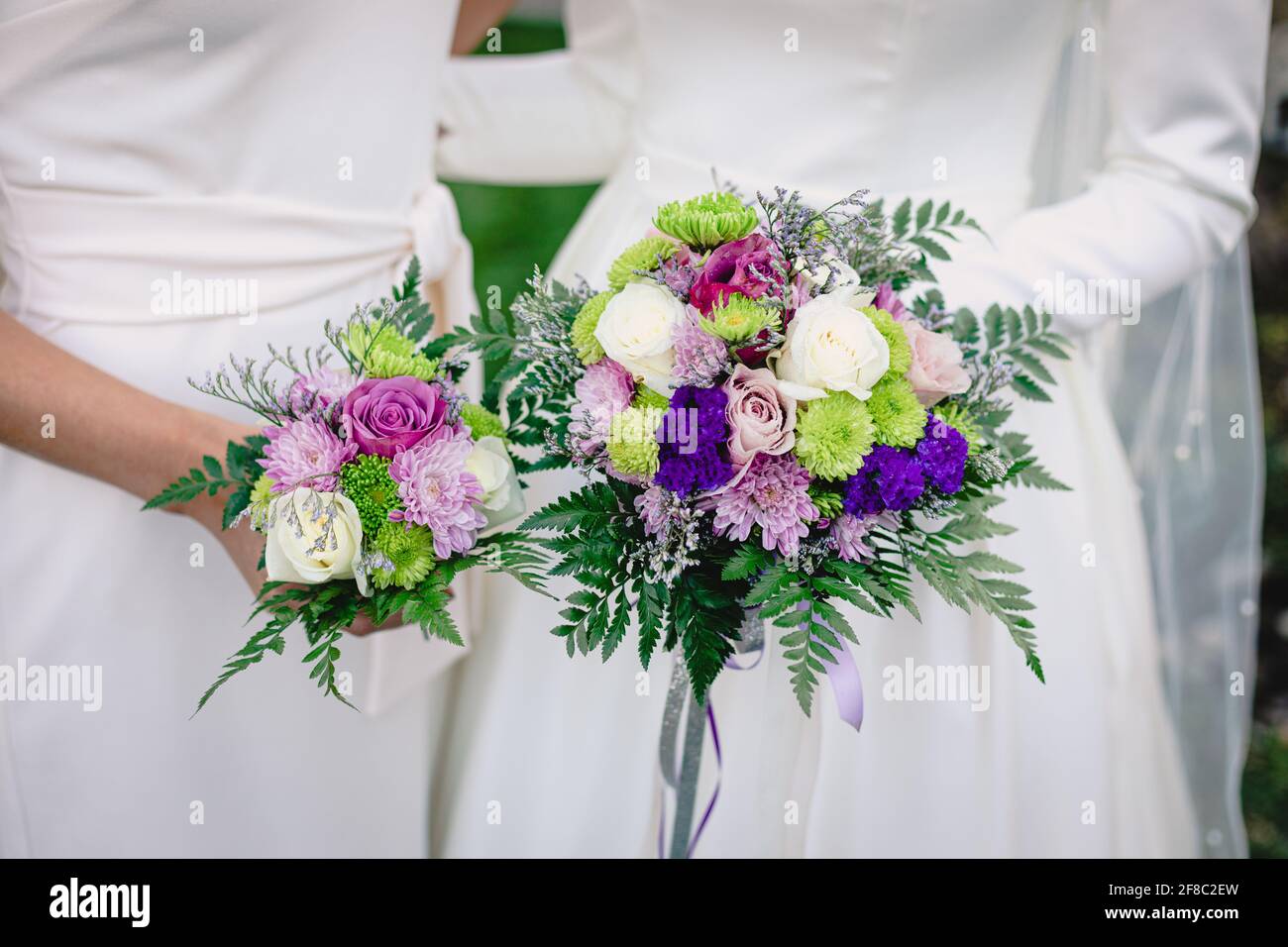La novia y la dama de honor tienen ramos de bodas de blanco, púrpura y verde  Fotografía de stock - Alamy