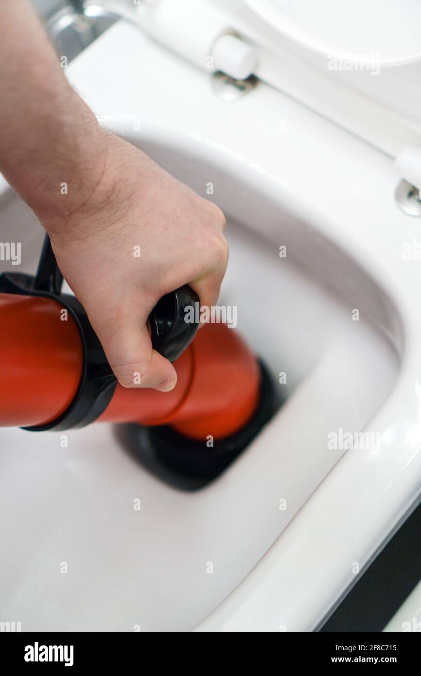 fontanero que desobstruye el inodoro con limpiador profesional de la bomba  de fuerza Fotografía de stock - Alamy