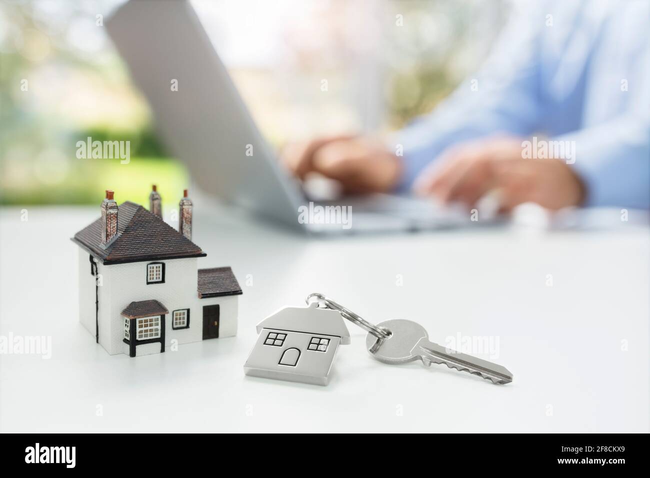 Buscando en Internet bienes raíces o nueva casa con modele el hogar y la llave Foto de stock