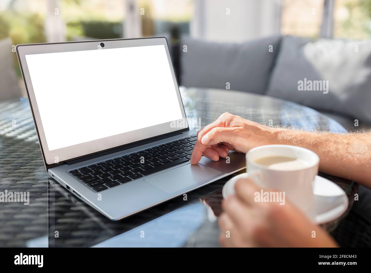 Hombre con ordenador portátil en el escritorio trabajando en la cafetería o. oficina con pantalla en blanco Foto de stock