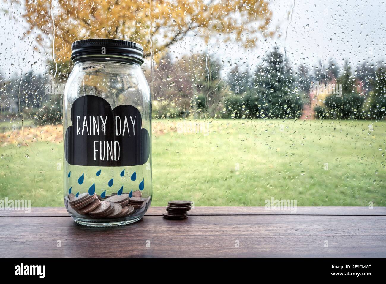 Ahorros para un día lluvioso fondo tarro de cristal con dinero Foto de stock