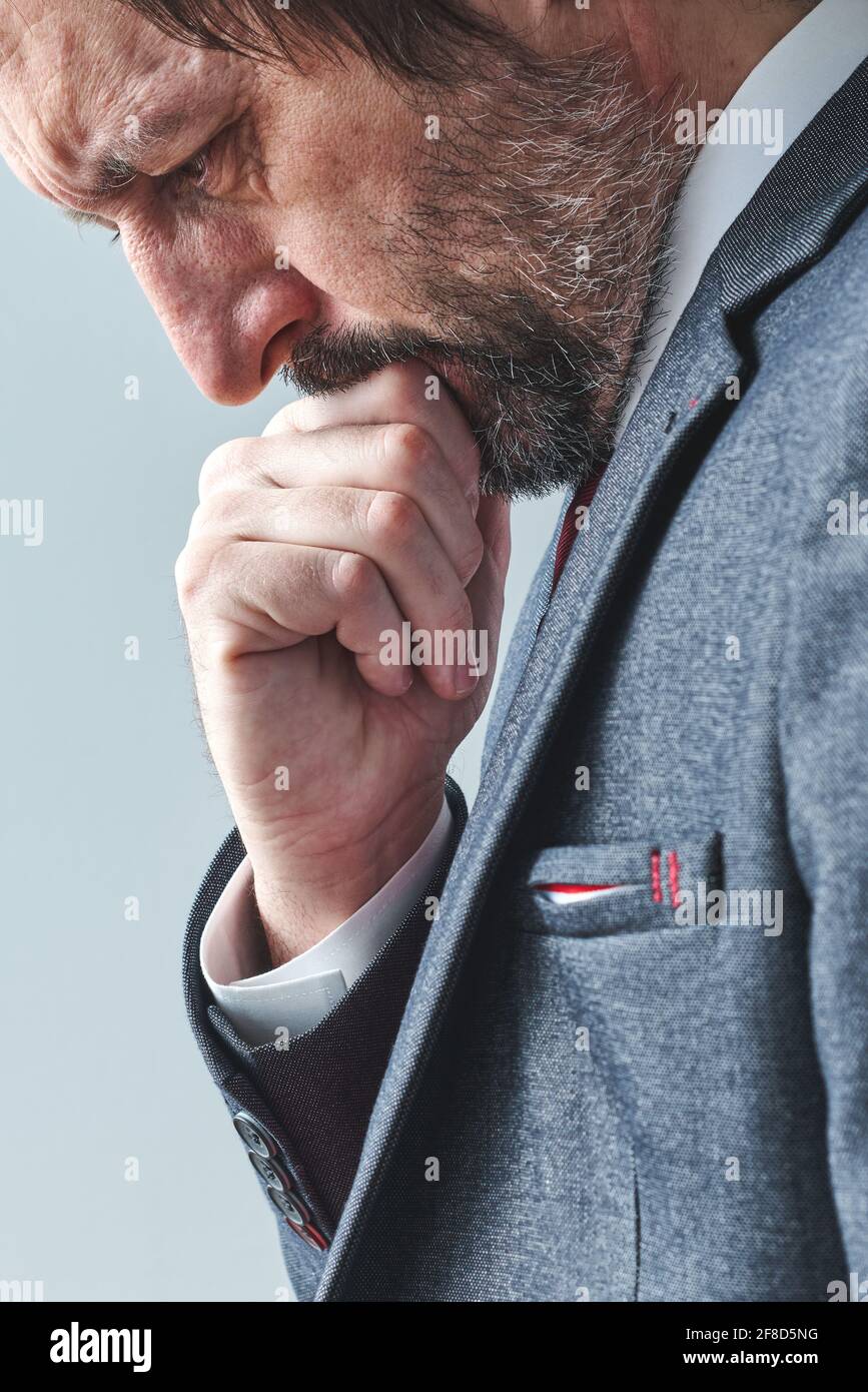 Hombre de negocios pensante sobrecargado de pensamientos pensando con la mano en la barbilla, retrato de enfoque selectivo, imagen vertical Foto de stock