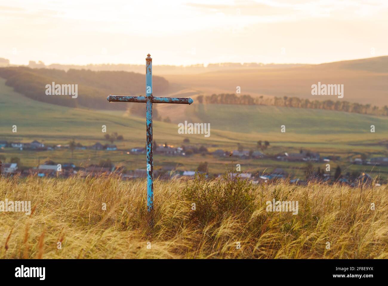 cruz religiosa en el campo. Cruce en el fondo del pueblo. Cruz Ortodoxa. Cruz católica Foto de stock