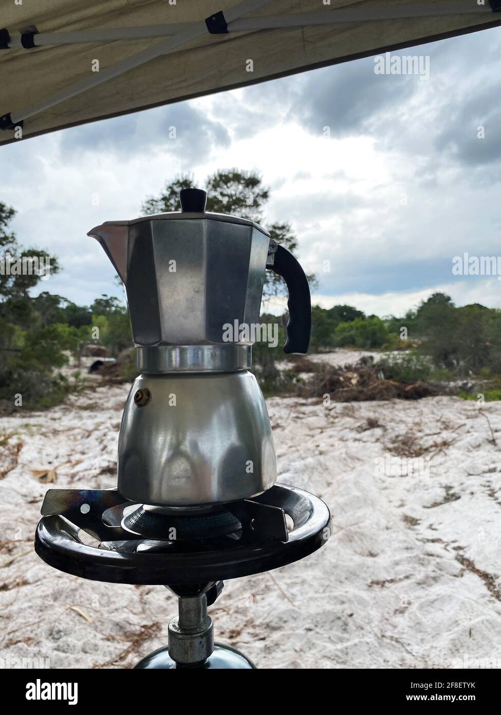 Café expreso en una cafetera cubana usando una mini cocina de gas con un  tanque de propano en una sola hornilla. Una tormenta se está gestando en el  fondo Fotografía de stock 