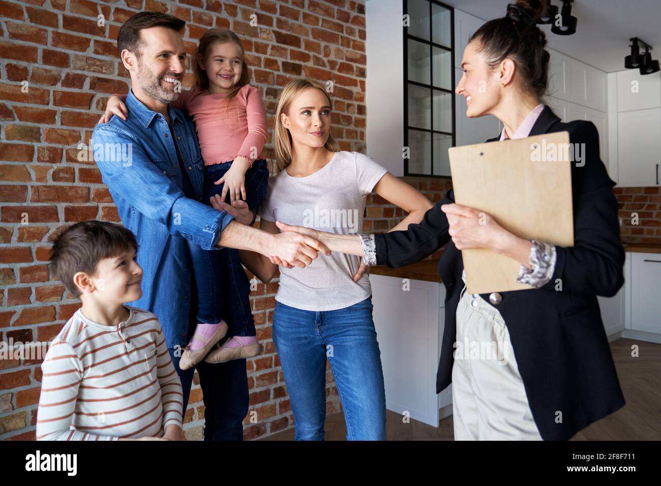Familia que se agita las manos con agente de bienes raíces en los nuevos apartamentos Foto de stock