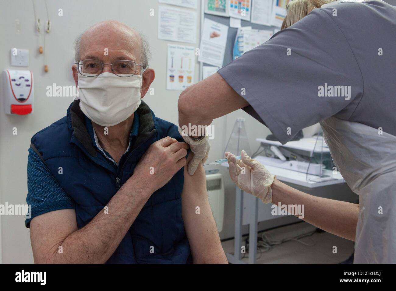 Henley-on-Thames, Reino Unido, 14 de abril de 2021: David Watson, de 77 años, recibe su segunda dosis de la vacuna contra el coronavirus de Oxford AstraZeneca de Eileen McClure Fisher, un dentista que está trabajando como voluntario en la práctica de Bell Surgery GP como parte del despliegue de vacunación del NHS. Más de 8 millones de personas en grupos prioritarios han recibido su segunda dosis y más de 32 millones de sus primeras dosis, y ahora se permite a las personas del grupo de 45-50 años reservar sus costras en Inglaterra, ya que los objetivos se cumplieron antes de lo previsto. Anna Watson/Alamy Live News Foto de stock