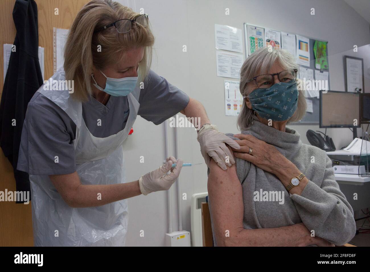 Henley-on-Thames, Reino Unido, 14 de abril de 2021: Helen Watson, de 77 años, recibe su segunda dosis de la vacuna contra el coronavirus de Oxford AstraZeneca de Eileen McClure Fisher, un dentista que está trabajando como voluntaria en la práctica de Bell Surgery GP como parte del despliegue de vacunación del NHS. Más de 8 millones de personas en grupos prioritarios han recibido su segunda dosis y más de 32 millones de sus primeras dosis, y ahora se permite a las personas del grupo de 45-50 años reservar sus costras en Inglaterra, ya que los objetivos se cumplieron antes de lo previsto. Anna Watson/Alamy Live News Foto de stock