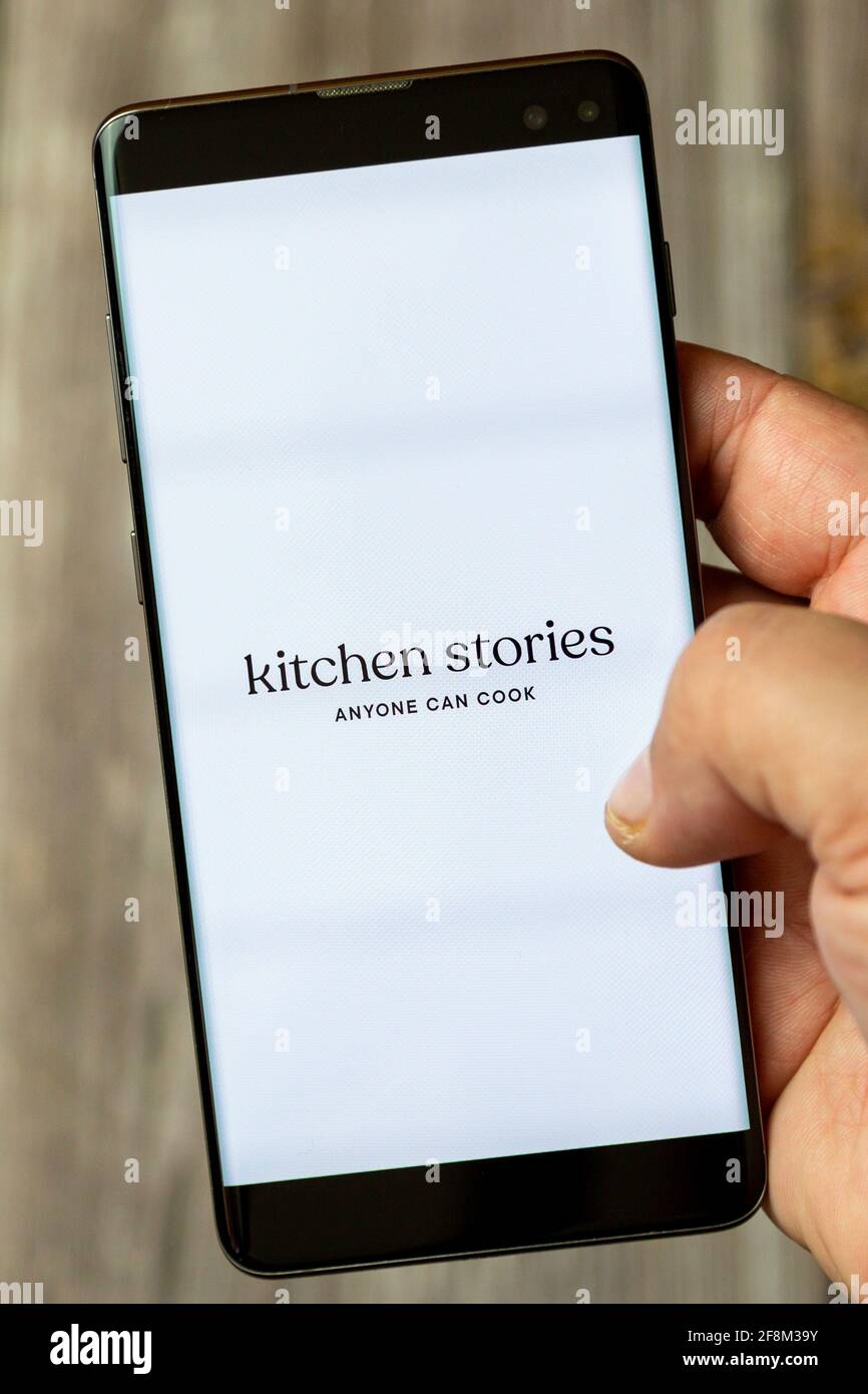 Un teléfono móvil o un teléfono móvil que se esté reteniendo en un mano que muestra la aplicación de historias de cocina en pantalla Foto de stock