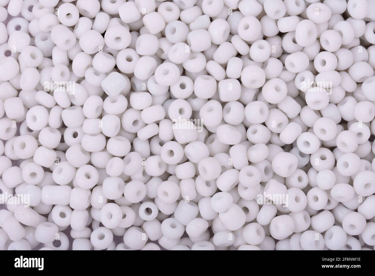 Cuentas blancas sobre el fondo blanco primer plano, macro, hacer collar de abalorios Foto de stock