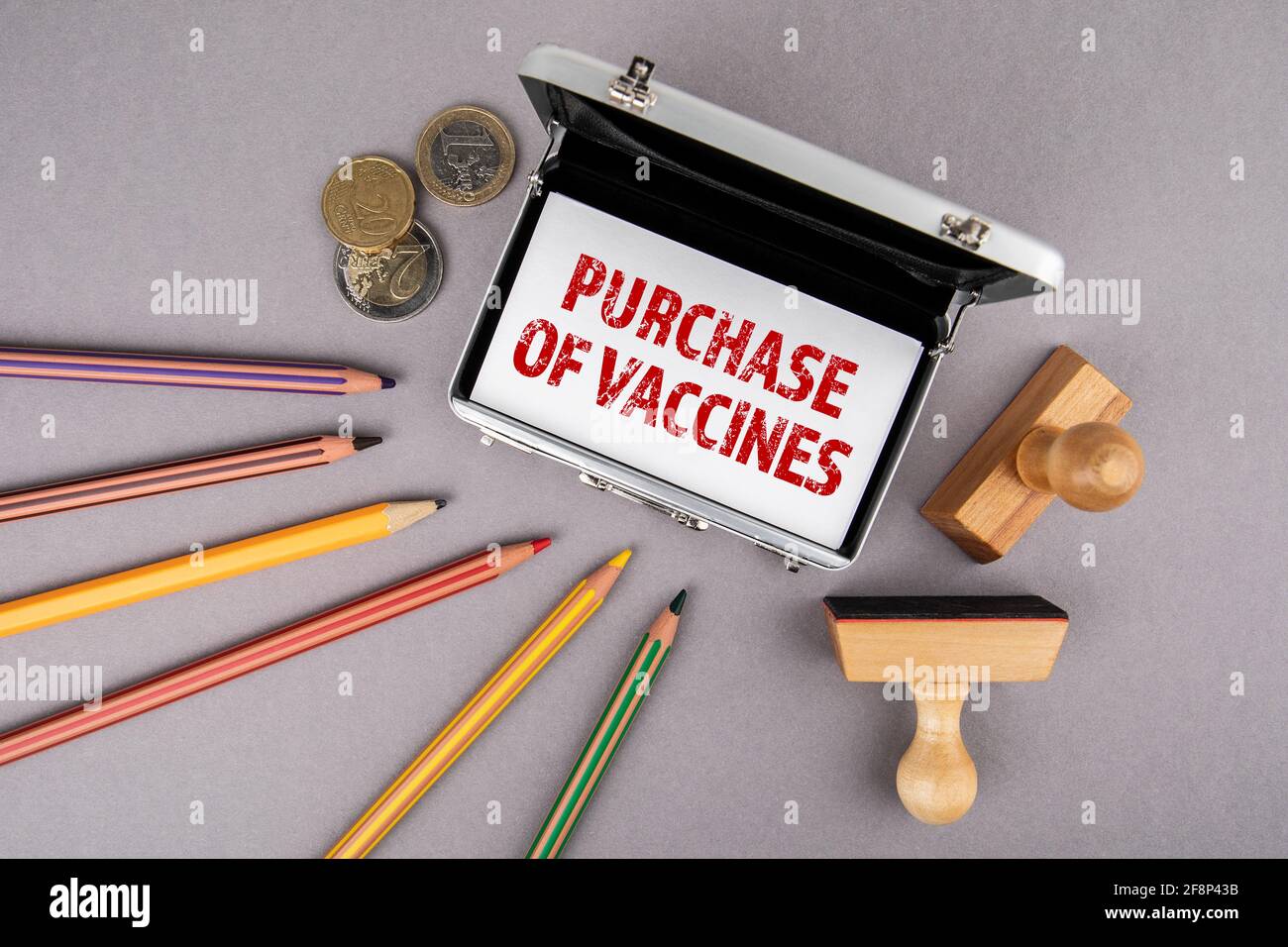 Compra de vacunas. Tarjetas de visita, lápices de colores y dinero en euros en un escritorio de oficina gris. Foto de stock