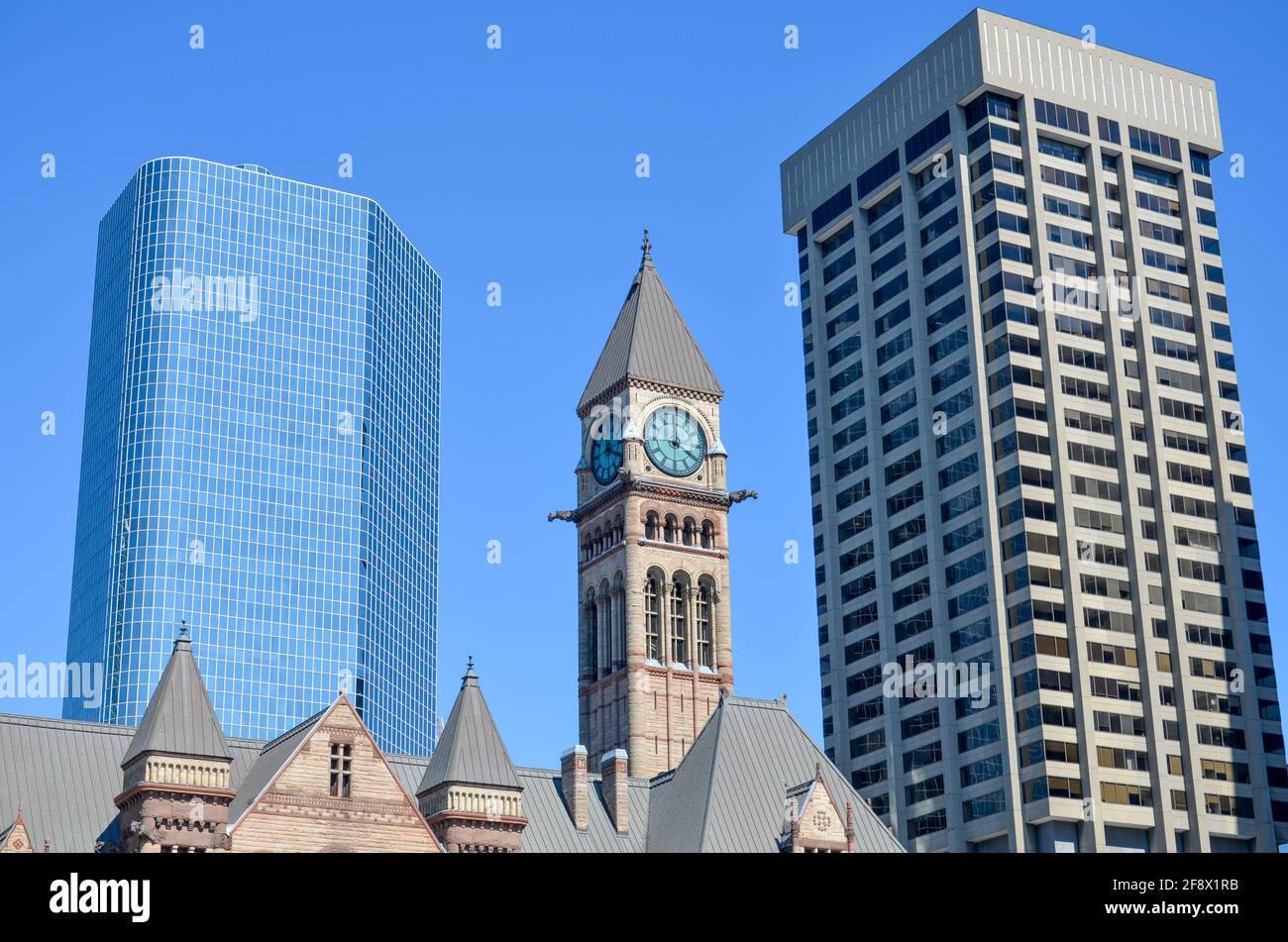 Antigua iglesia con el reloj de la torre de la iglesia entre algunos edificios de oficinas En el centro de Toronto bajo un soleado cielo azul Foto de stock