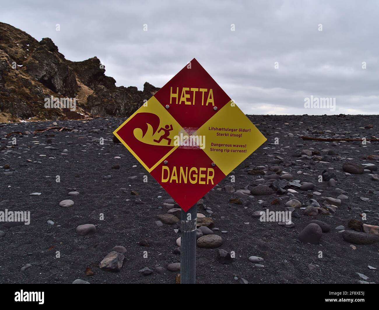 Vista de primer plano de señales de color rojo y amarillo que advierten de las fuertes corrientes en la playa de Djupalonssandur en la costa de la península de Snaefellsnes. Foto de stock