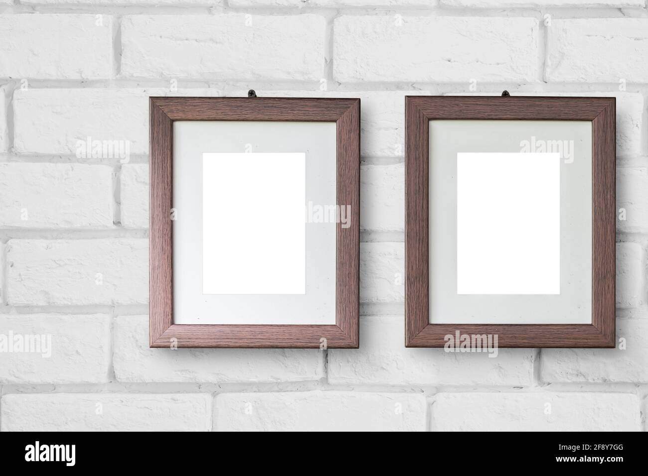 Hermoso marco de dos cuadros de madera colgando en la pared de ladrillo blanco para parejas amantes fotos de estilo moderno simple mínimo Foto de stock