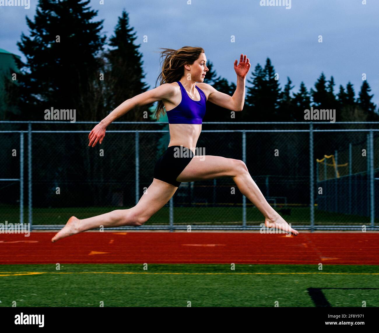 Mujer joven corriendo por la pista Foto de stock