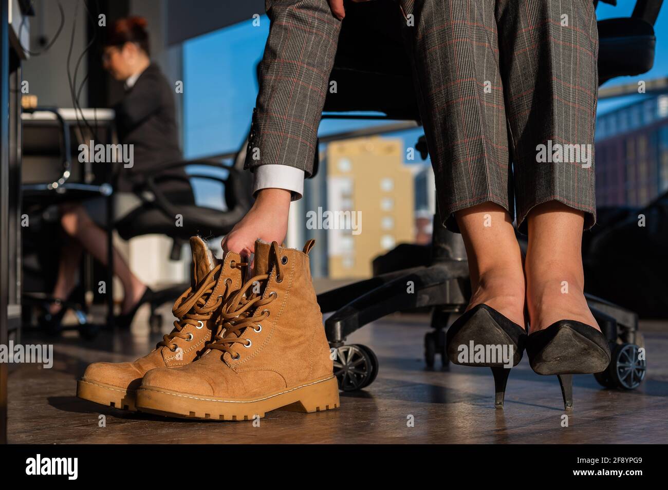 Mujer de negocios cambia de zapatos con tacones altos en las botas en la  oficina. Fin del día de trabajo. Piernas cansadas Fotografía de stock -  Alamy