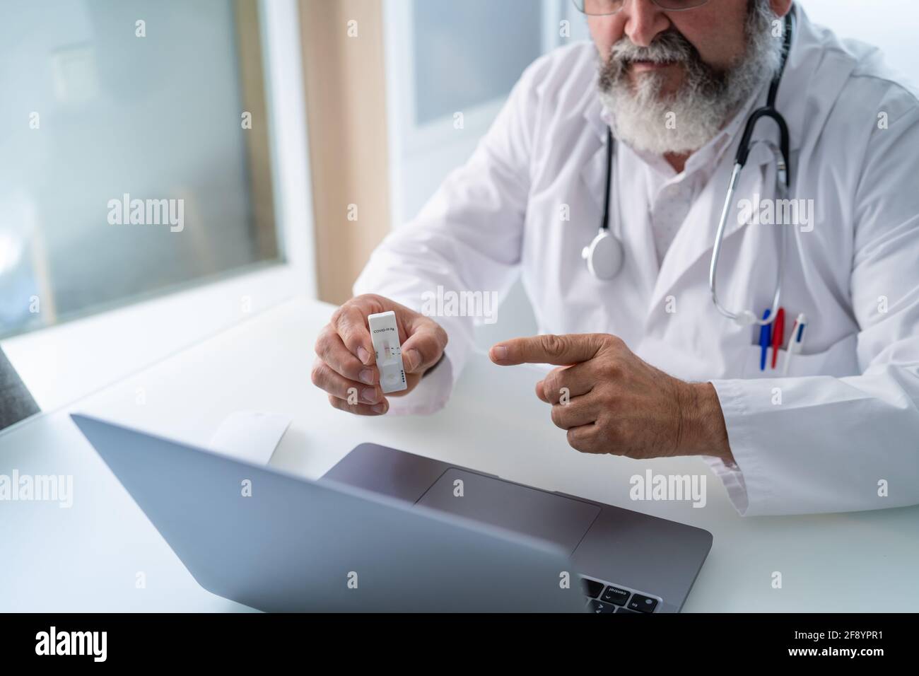 Médico de la tercera edad que tiene una videoconferencia con un paciente que muestra Resultado de la prueba de PCR Covid-19 Foto de stock