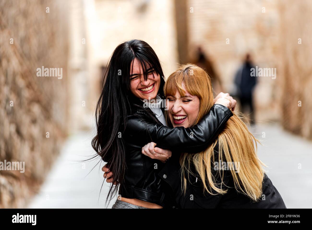 Rubia y mujer morena abrazándose felizmente. Foto de stock