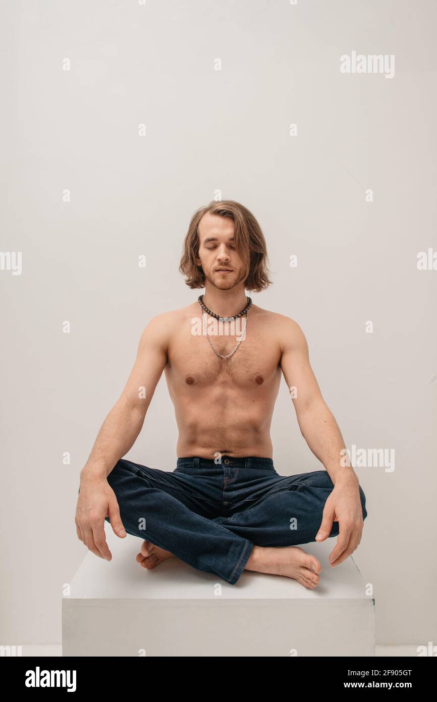 Retrato de un hombre sin camisa sentado con patas cruzadas sobre una caja Foto de stock