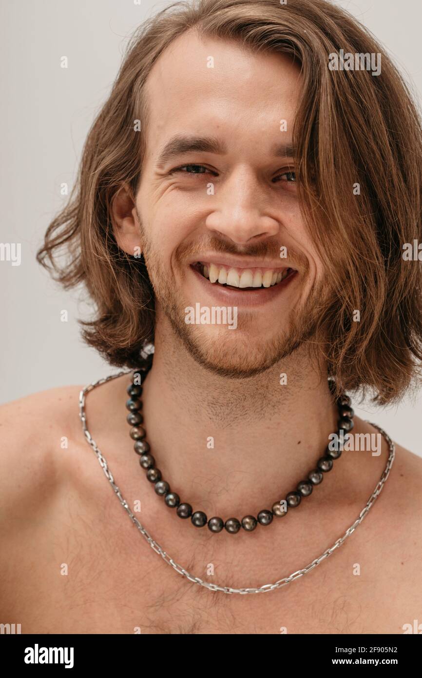 Retrato de un hombre sonriente sin camisa que lleva collares Foto de stock