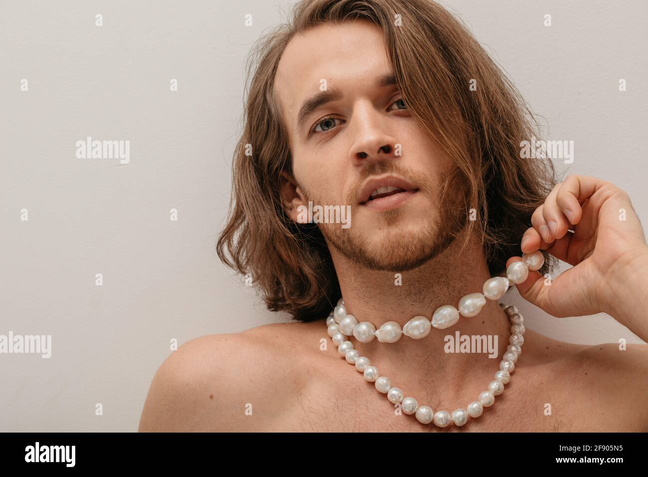Retrato de un hombre sin camisa con collares de perlas Foto de stock