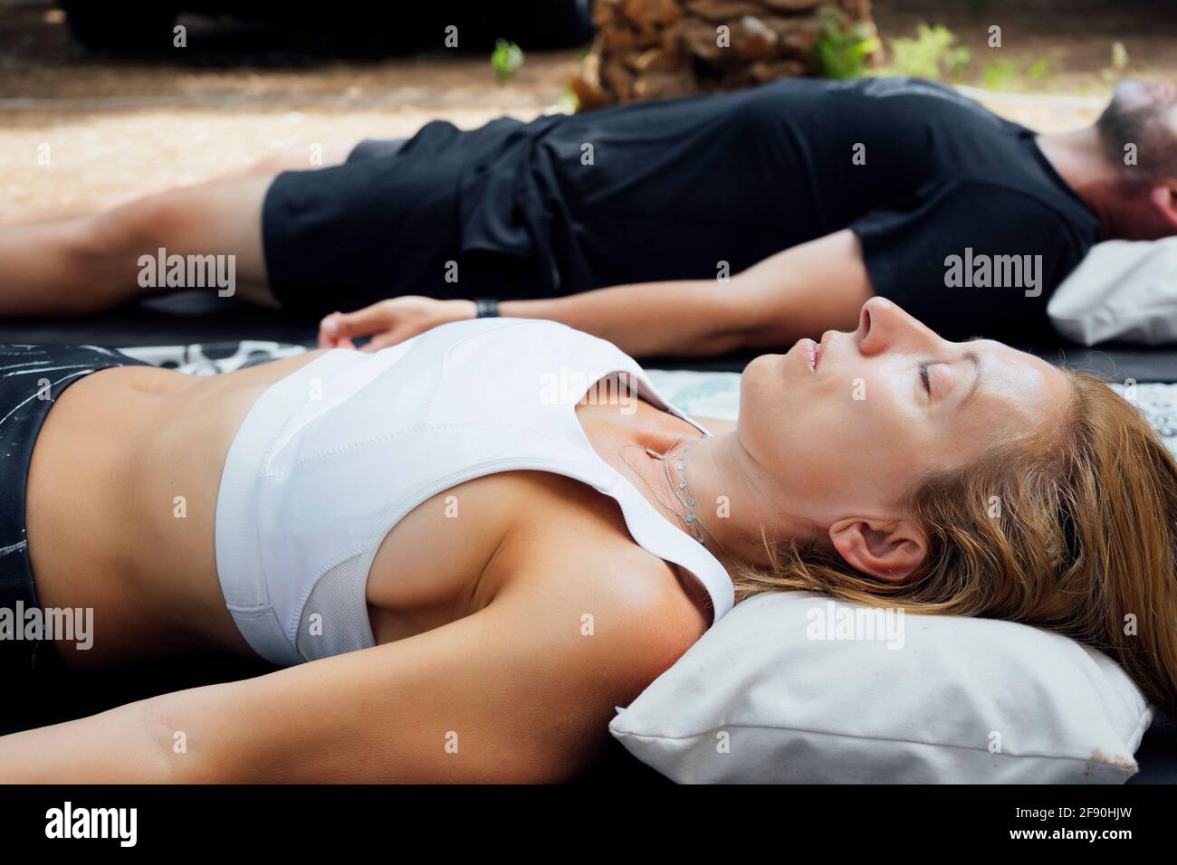 Primer plano de la hermosa atractiva mujer europea que practica yoga Dead Body pose o Savasana pose acostado en la colchoneta de yoga para la meditación de yoga sensación de relajarse y sentirse cómodo, concepto de salud Foto de stock