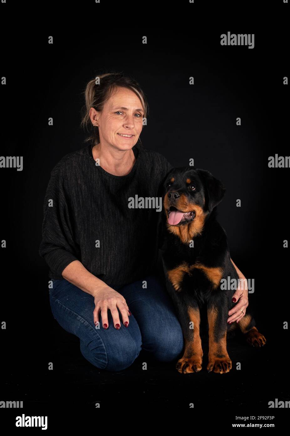 purebred rottweiler y mujer delante de fondo negro Foto de stock