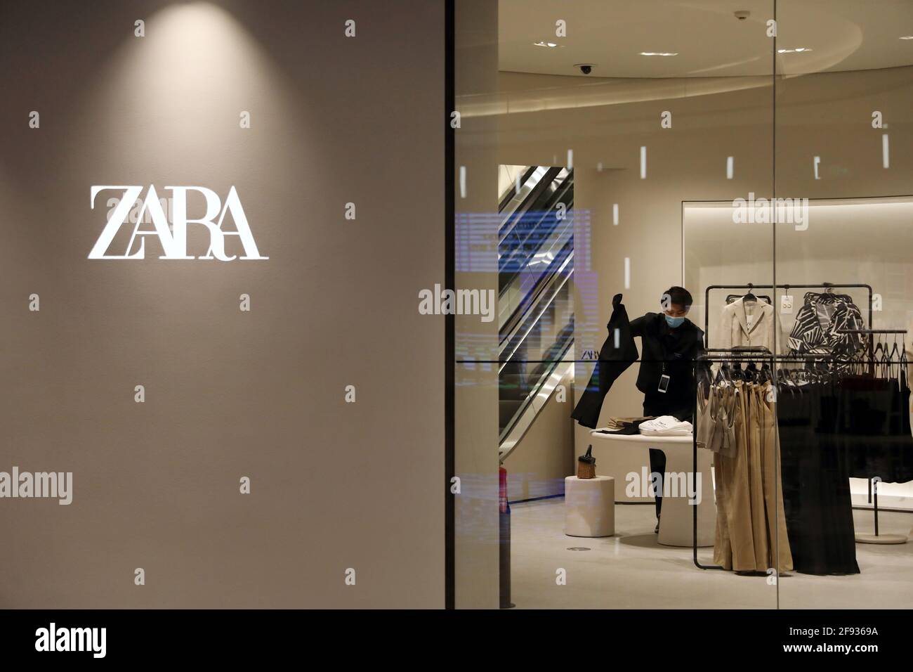 Un miembro del personal clasifica la ropa dentro de una tienda de ropa de  la marca Zara de Inditex en un centro comercial recién inaugurado en  Beijing, China, el 16 de abril