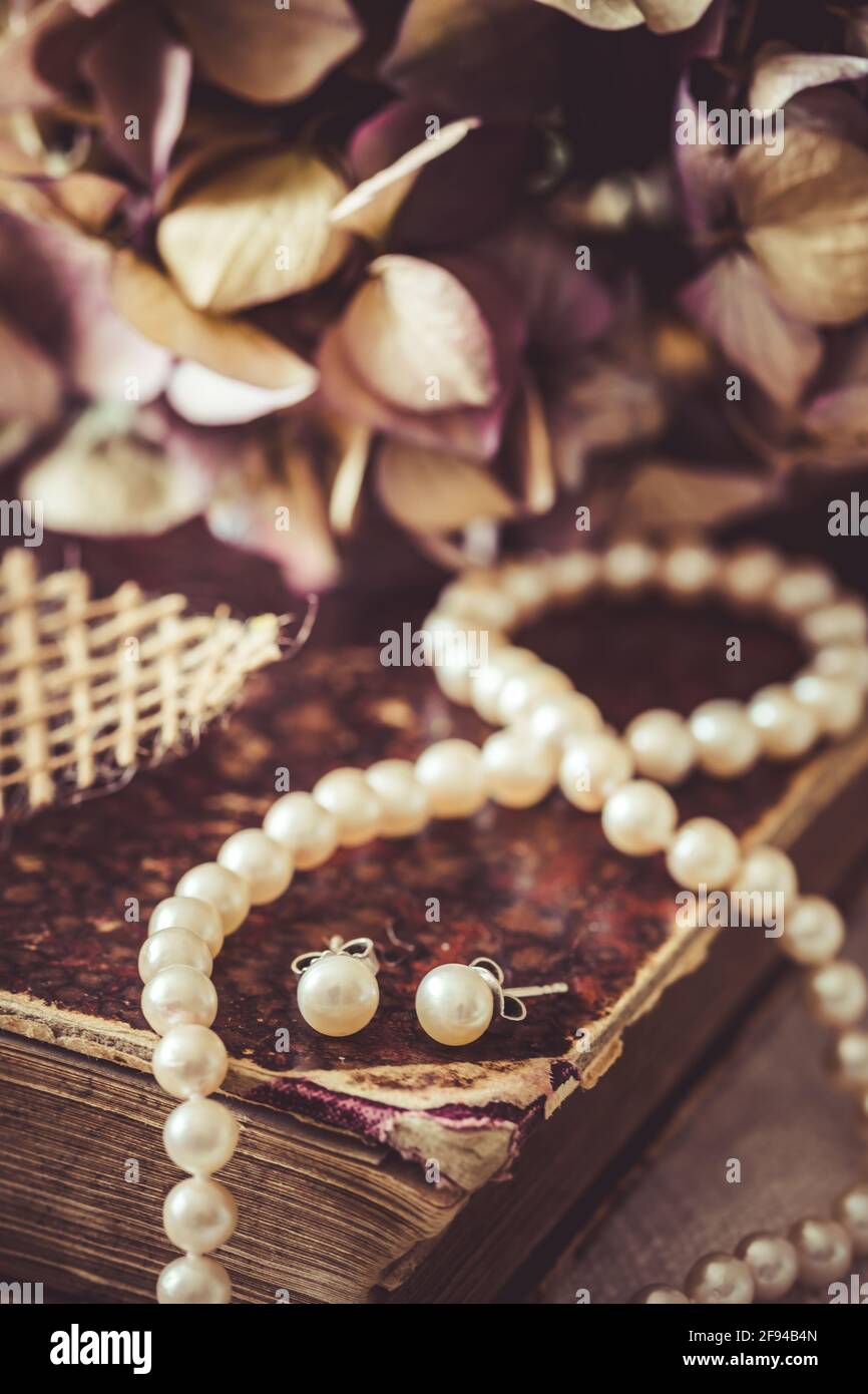 Collar de perlas blancas y pendientes en un libro antiguo, estilo vintage,  vertical, primer plano Fotografía de stock - Alamy