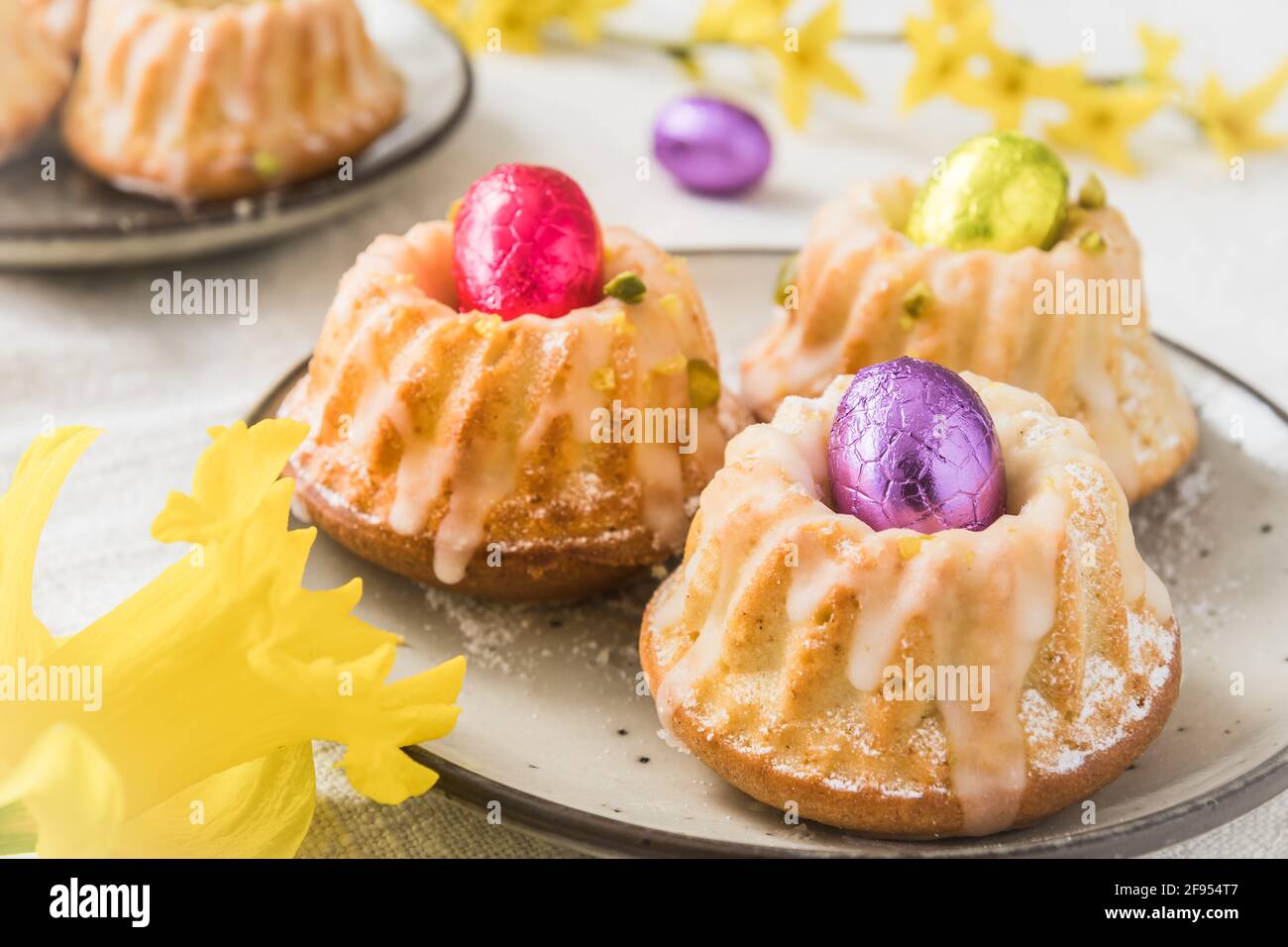 Deliciosas tortas caseras de bollitos de limón (magdalenas) con huevos de chocolate en una mesa con flores de primavera Fotografía de stock - Alamy Deliciosas tortas caseras de bollitos de limón (magdalenas) con huevos de chocolate en una mesa con flores de primavera Fotografía de stock - Alamy