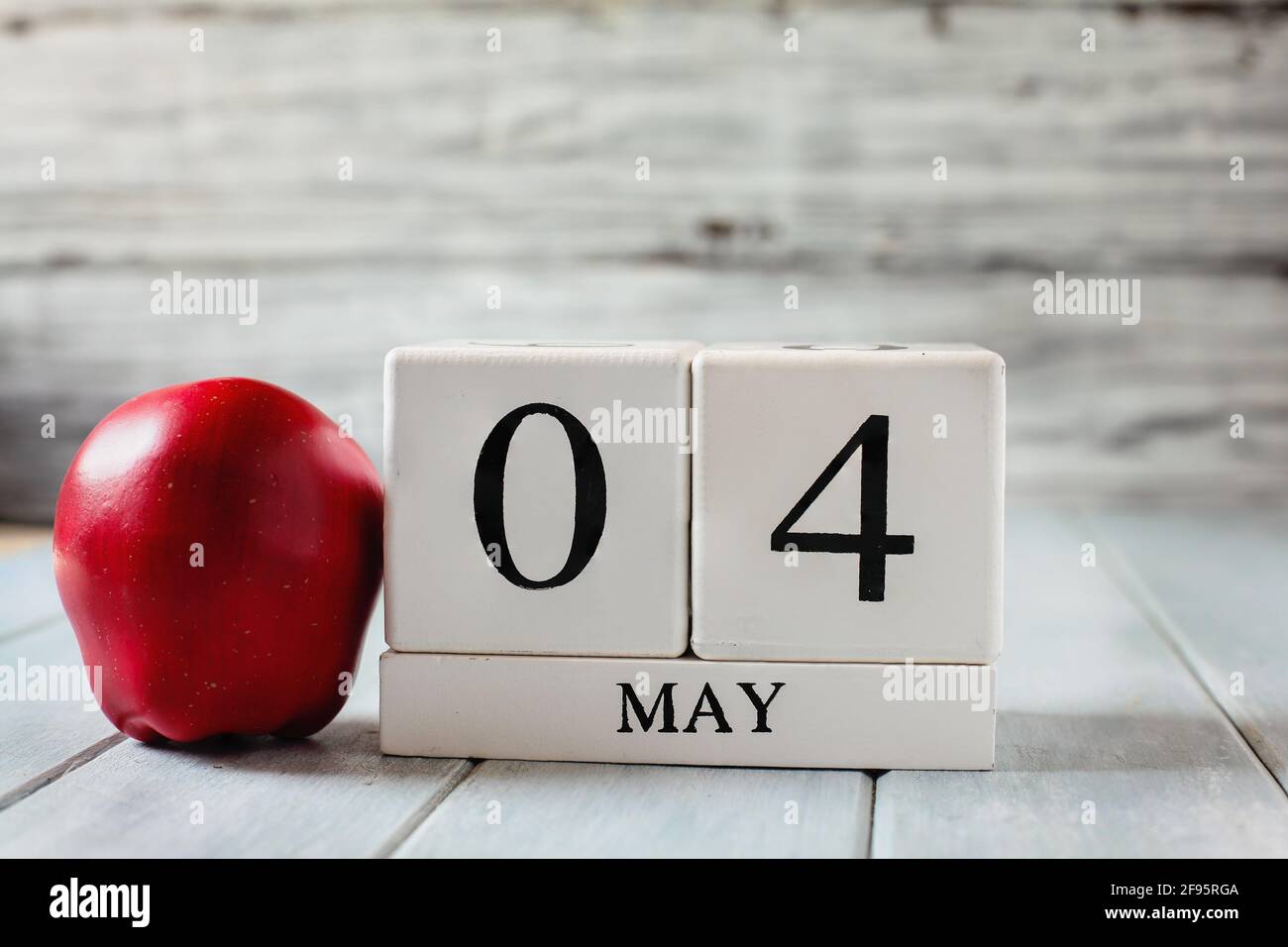 Bloques de calendario de madera blanca con la fecha del 4th de mayo y una manzana roja para el Día Nacional de Apreciación del Maestro. Foto de stock