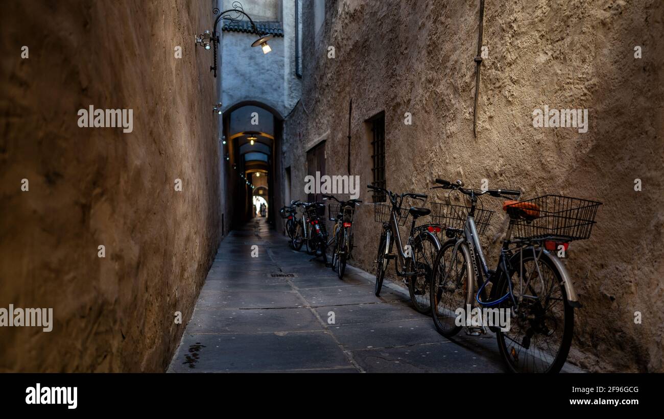 callejón oscuro estrecho, bicicletas, casco antiguo, fotografía callejera, luz al final Foto de stock