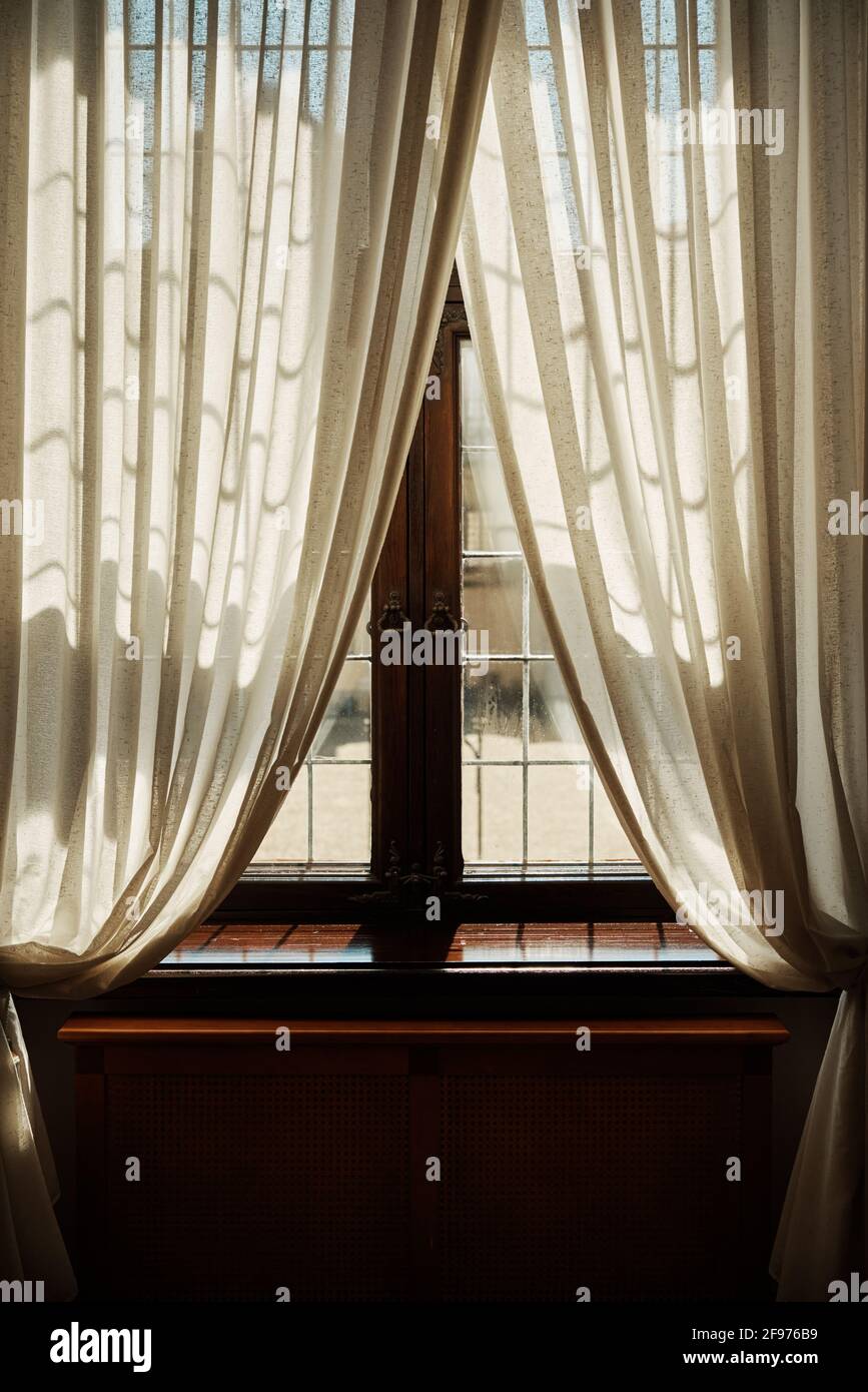 Ventana antigua con cortinas blancas y rayos brillantes de la sol  Fotografía de stock - Alamy