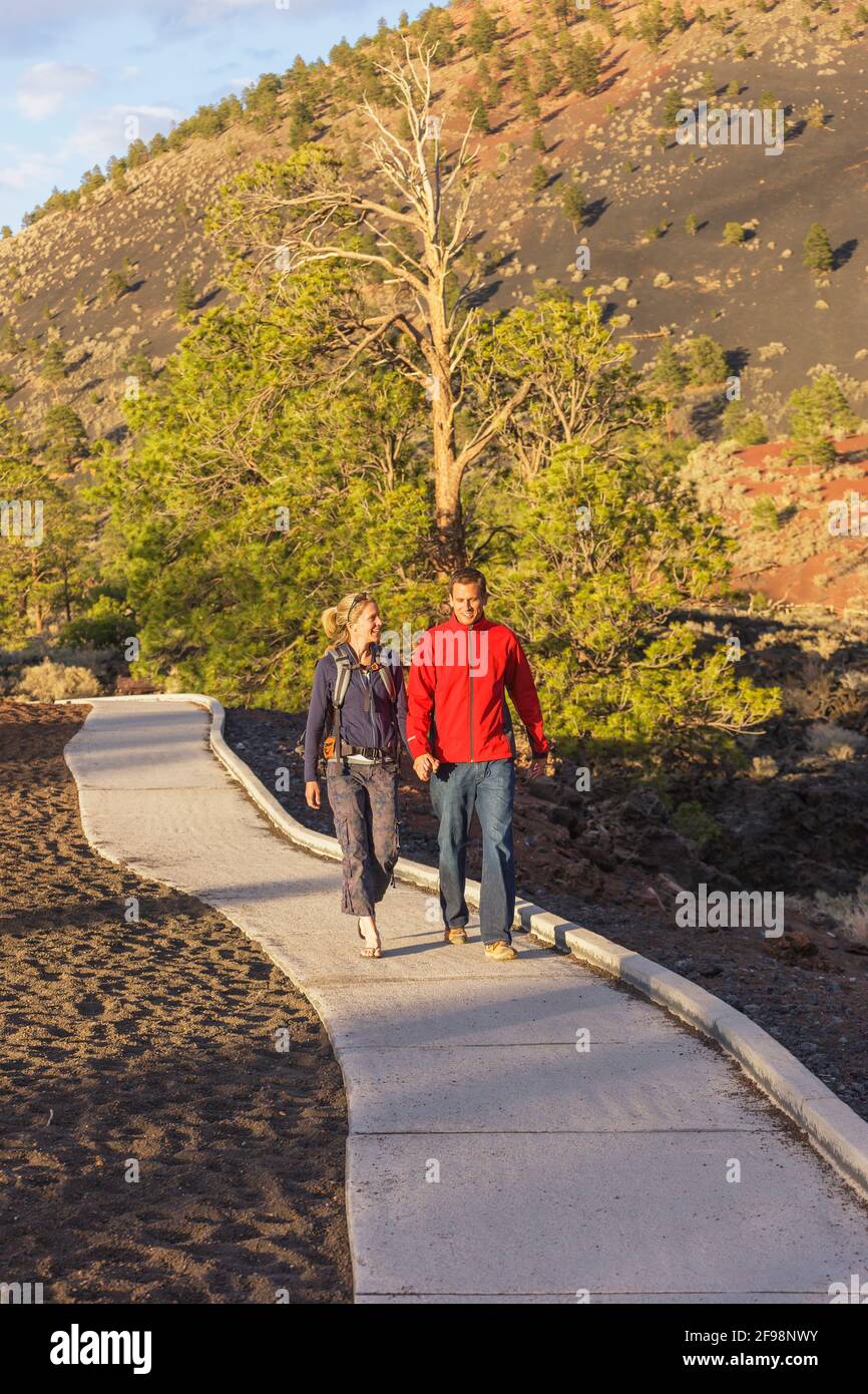 Pareja caminando por el camino, Sunset Crater Volcano National Monument, Flagstaff, Arizona, Estados Unidos Foto de stock