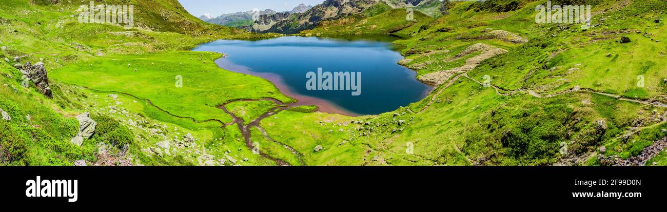 Lago de montaña azul virgen en un prado verde de montaña Foto de stock