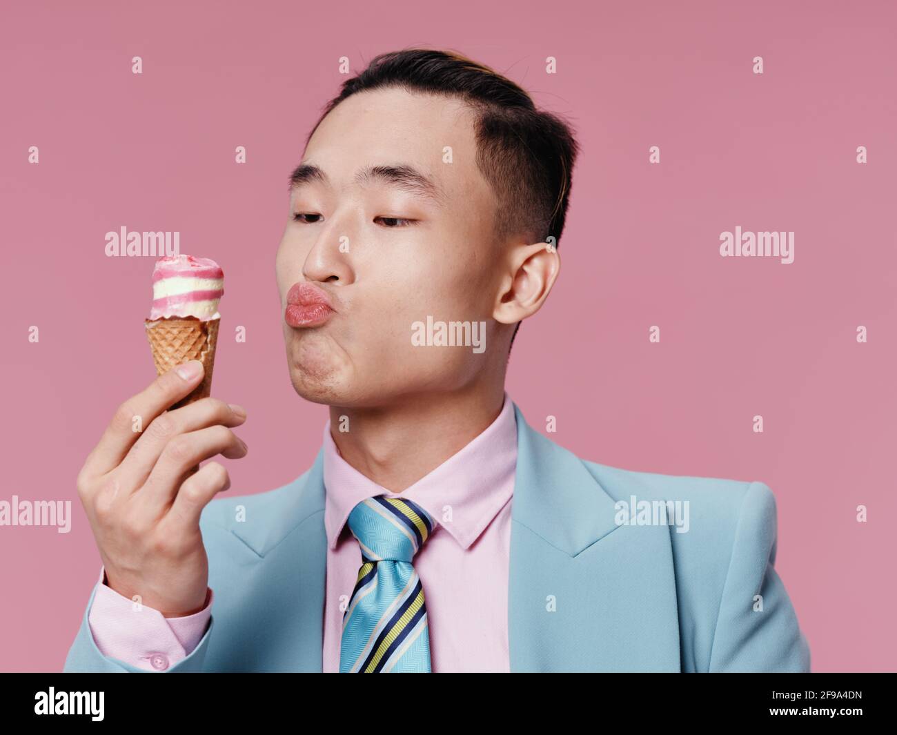 Hombre de moda con traje azul y camisa rosa sobre un fondo aislado con  helado en su mano Fotografía de stock - Alamy