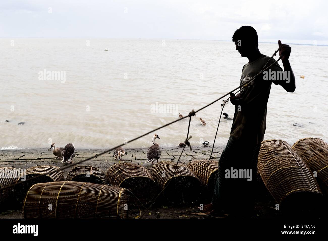 Pescador preparándose para la pesca en jaula y cuerda en la orilla del río Capturé esta imagen el 15th de septiembre de 2020 en Chandpur, Bangladesh Foto de stock