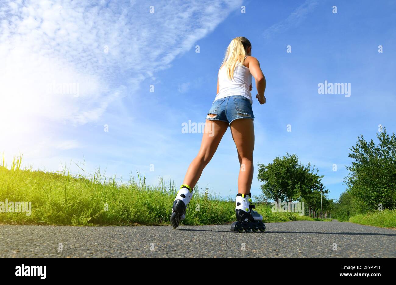 Adolescente en patines en el verano. Patinaje en línea en la carretera. Foto de stock