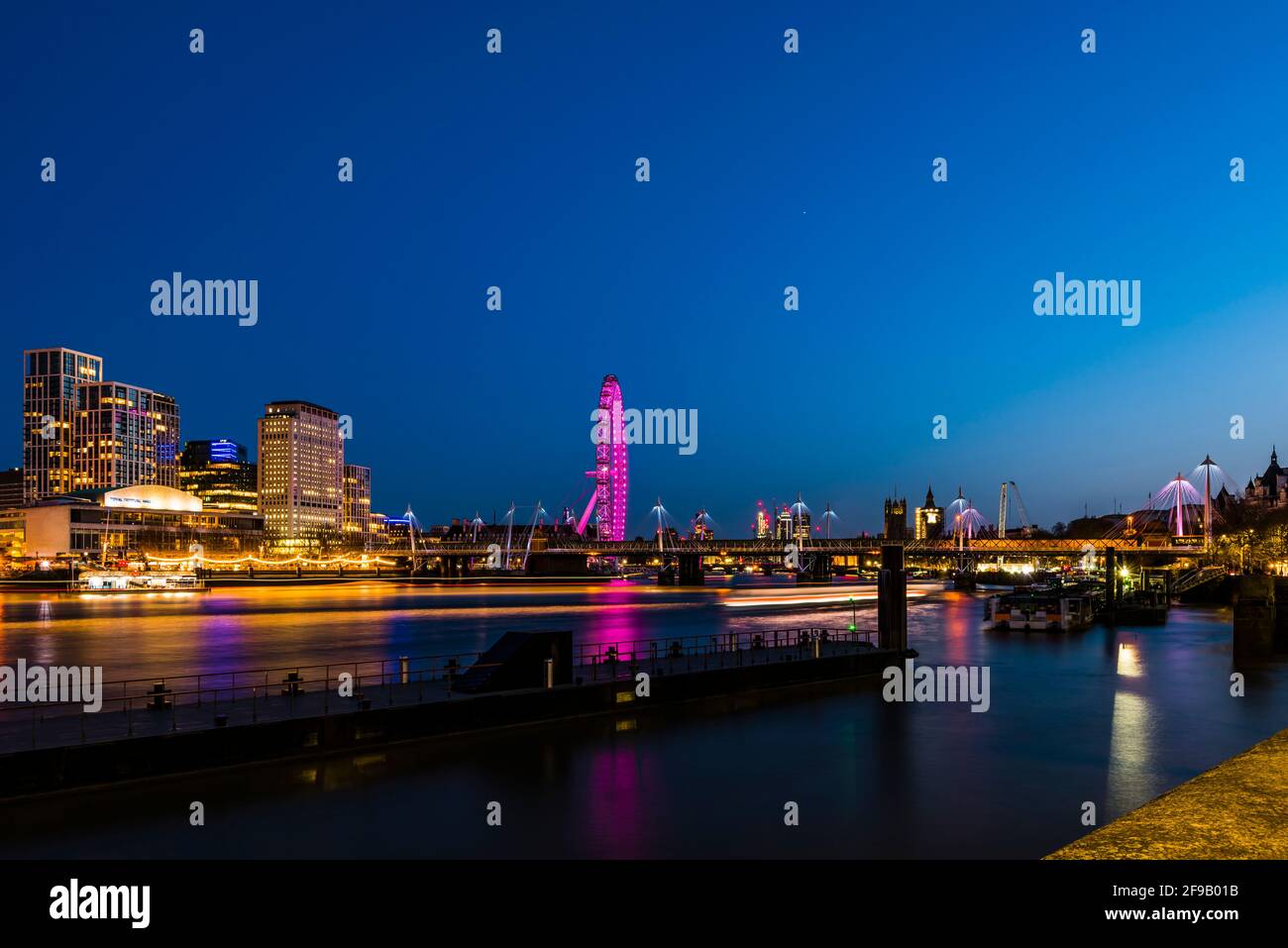 Luces y senderos para barcos en los puentes Hungerford y Golden Jubilee al atardecer, Londres, Reino Unido Foto de stock
