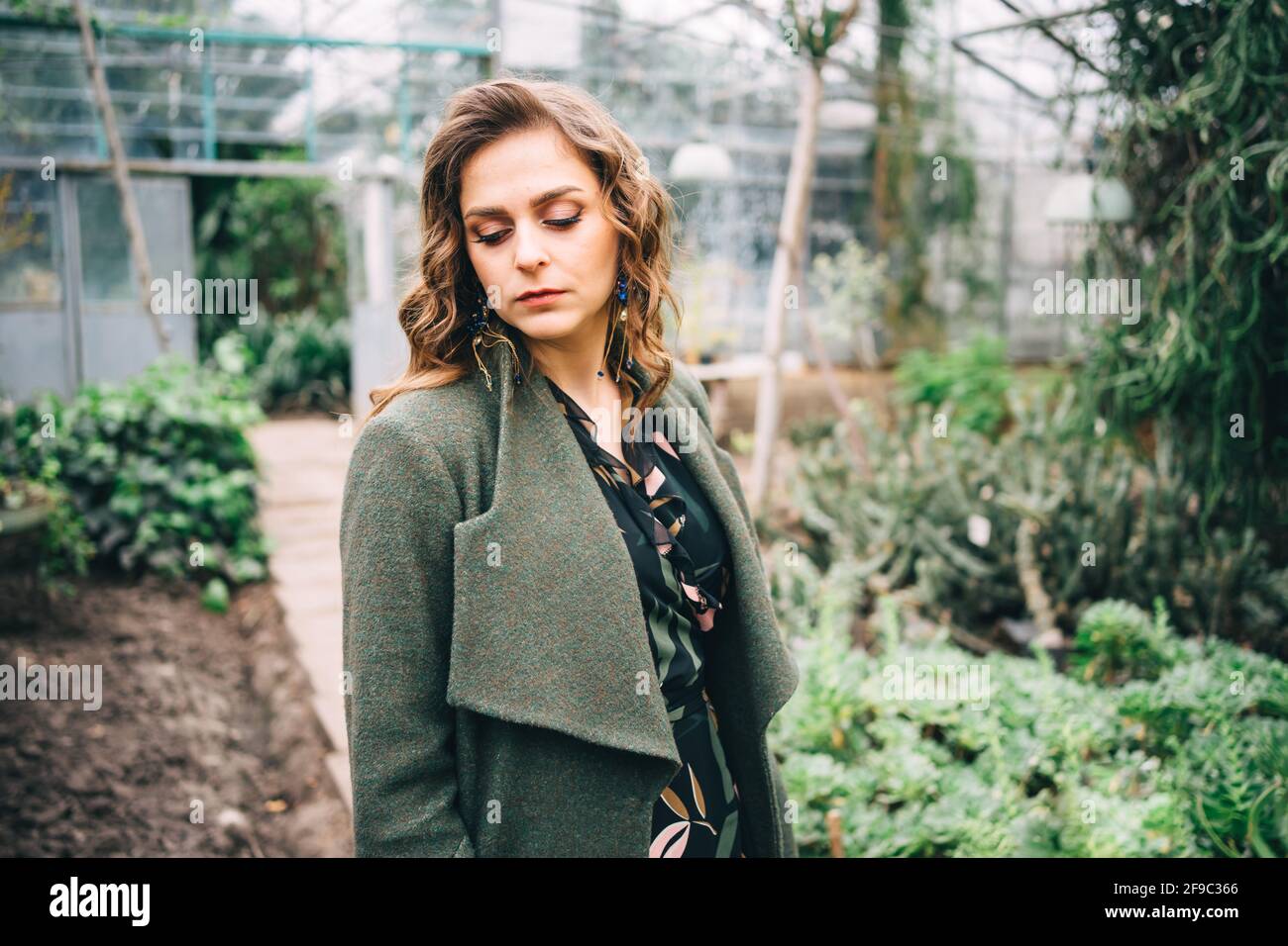 chica en un abrigo verde en un invernadero Foto de stock