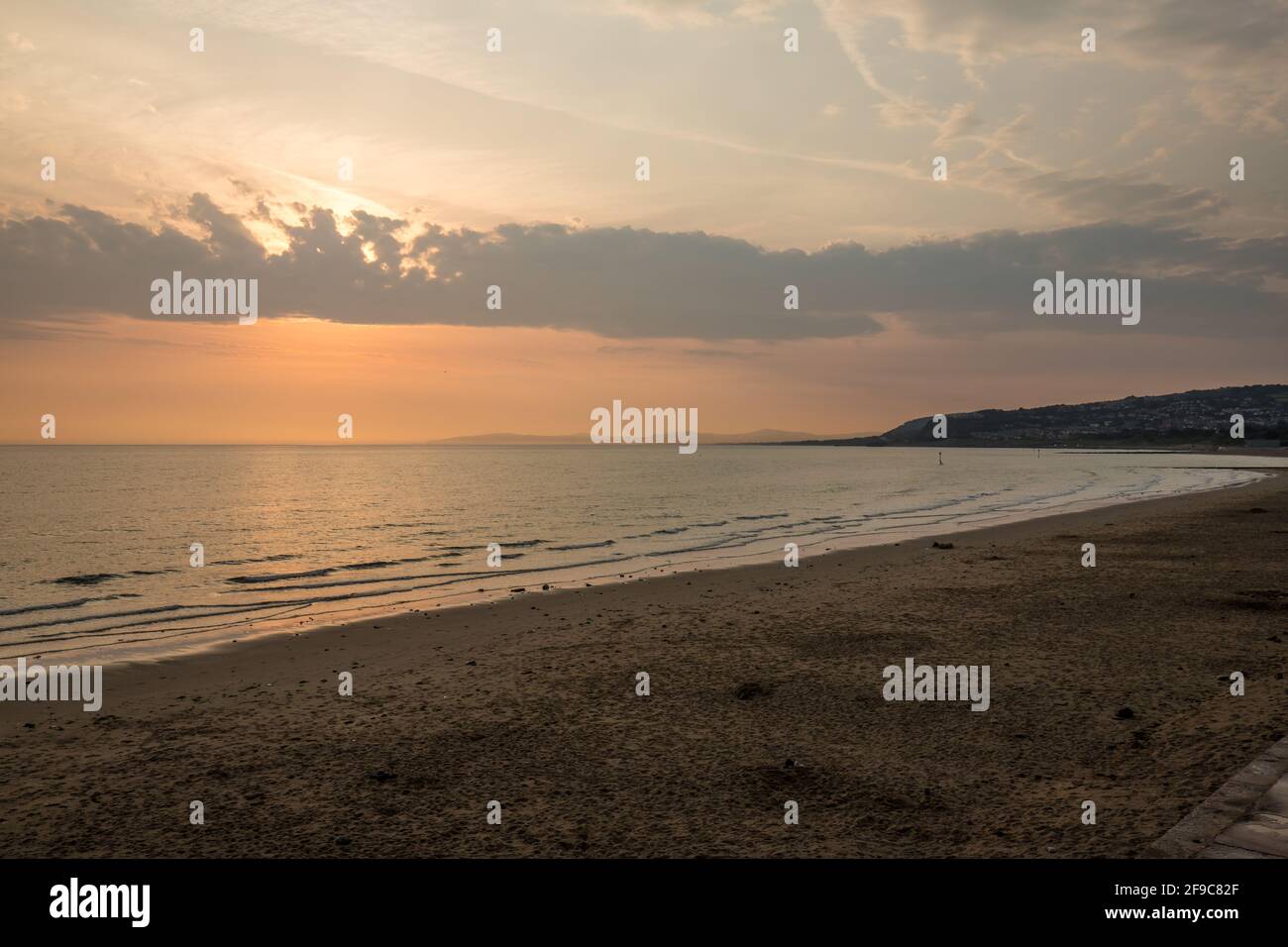 Espectacular cielo con rayos de sol sobre la bahía de Colwyn, Gales del Norte. Amanecer amanecer en la costa con un mar tranquilo Foto de stock