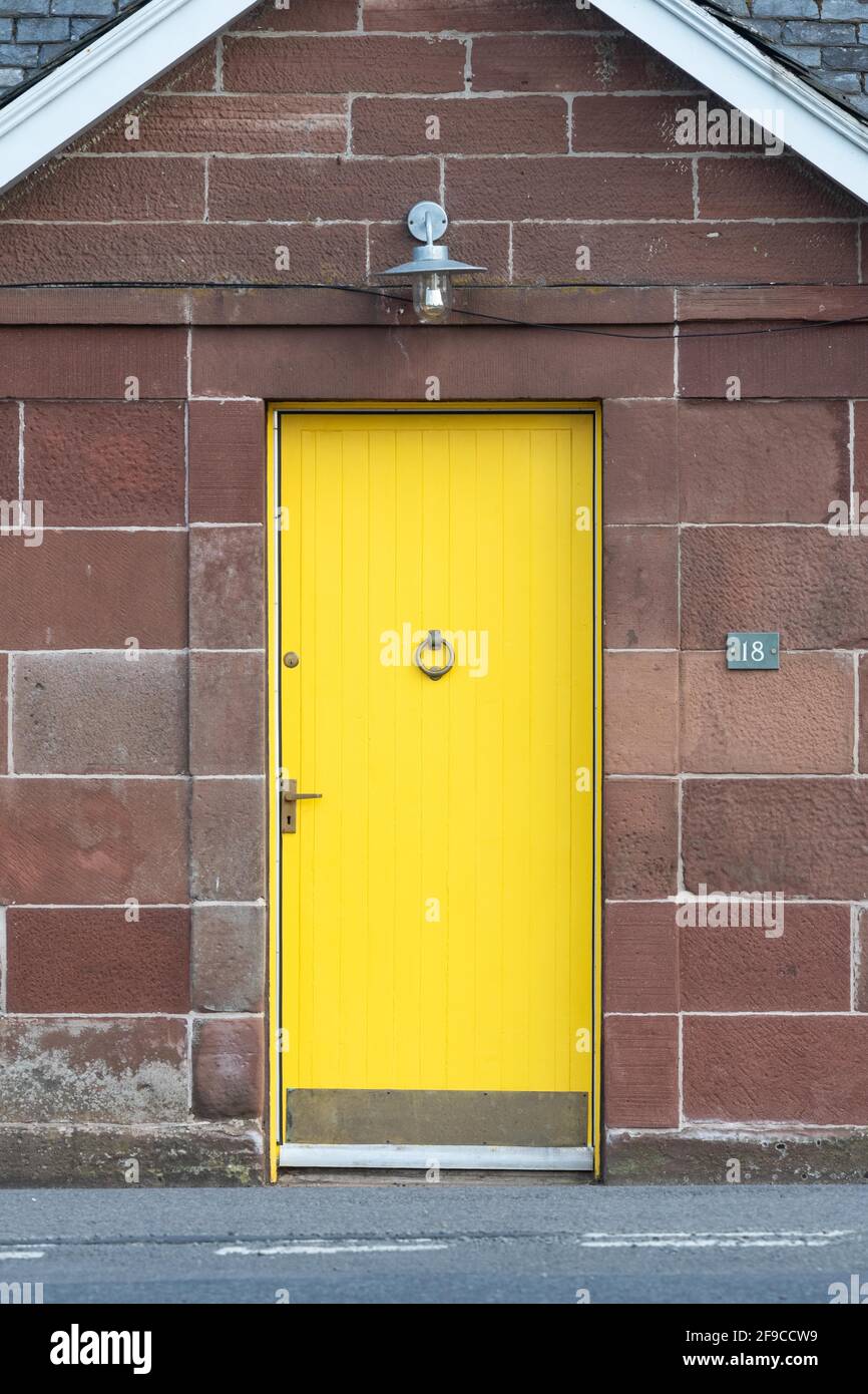 Puerta frontal amarilla en casa de campo de piedra arenisca roja - Escocia, Reino Unido Foto de stock