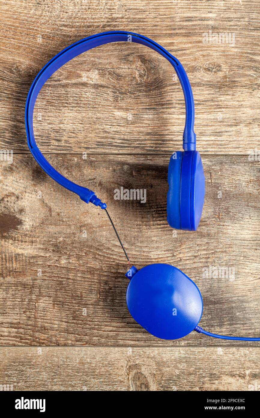 Imagen aislada de un auricular azul con banda ajustable para la cabeza. Uno de los auriculares está roto en el lado de conexión con los cables expuestos. Imagen conceptual Foto de stock