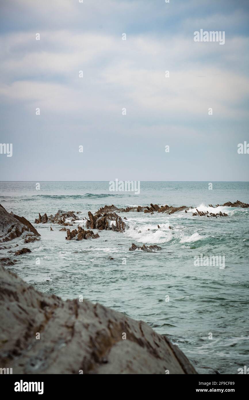 Playa Sakoneta en el norte de España llena de rocas afiladas que emergen desde el fondo del océano Foto de stock