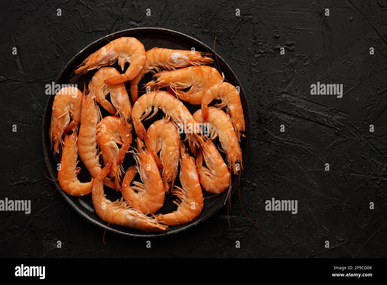 Langostinos de mar grandes hervidos o camarones colocados sobre cerámica negra placa Foto de stock