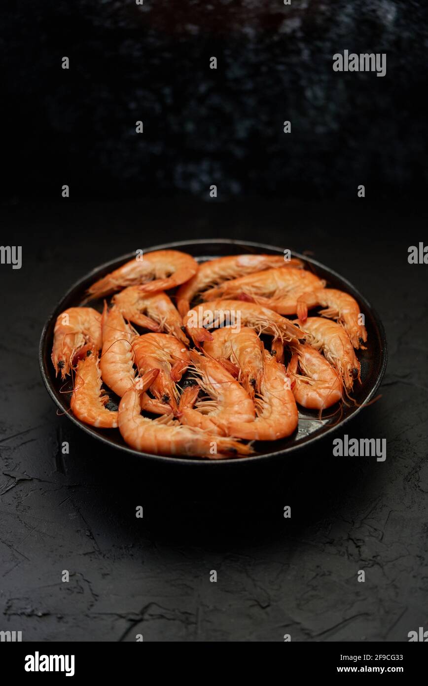Langostinos de mar grandes hervidos o camarones colocados sobre cerámica negra placa Foto de stock