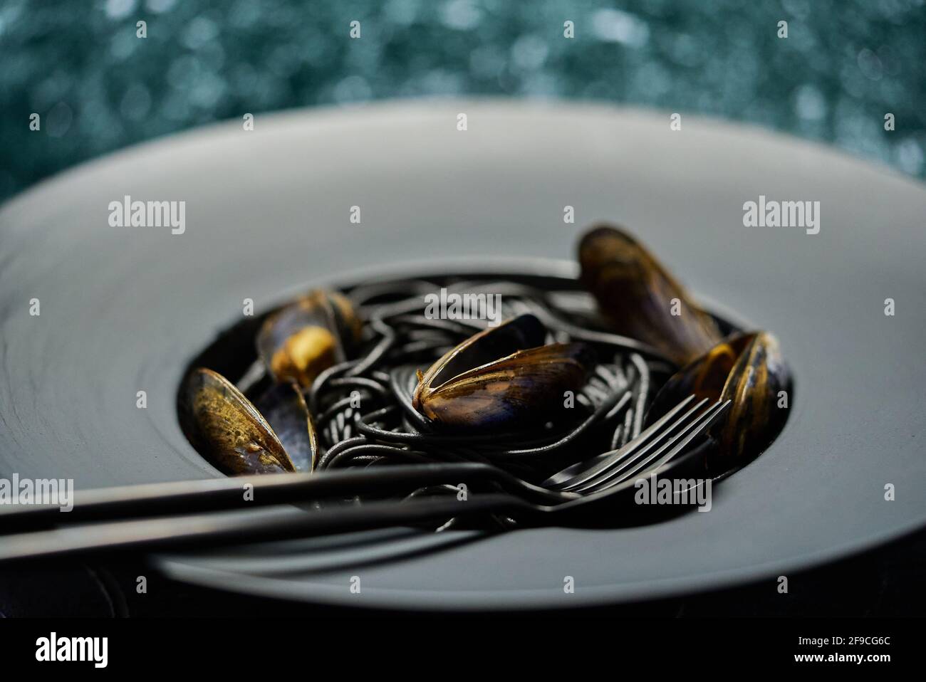 Pasta de espagueti negra de marisco con almejas servidas en plato negro sobre piedra oscura Foto de stock