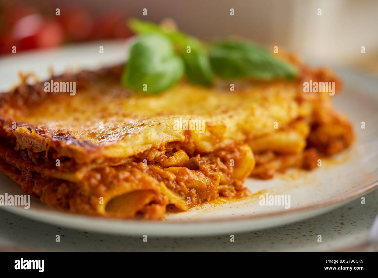 Sabrosas lasaña de carne casera con albahaca fresca y queso parmesano en un plato sobre fondo de madera Foto de stock