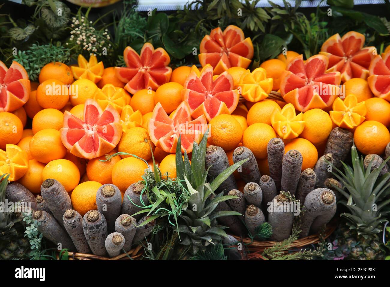 Imagen completa de pomelos, naranjas, zanahorias rojas y ananas en exhibición en el mostrador de una tienda de zumos de frutas Foto de stock
