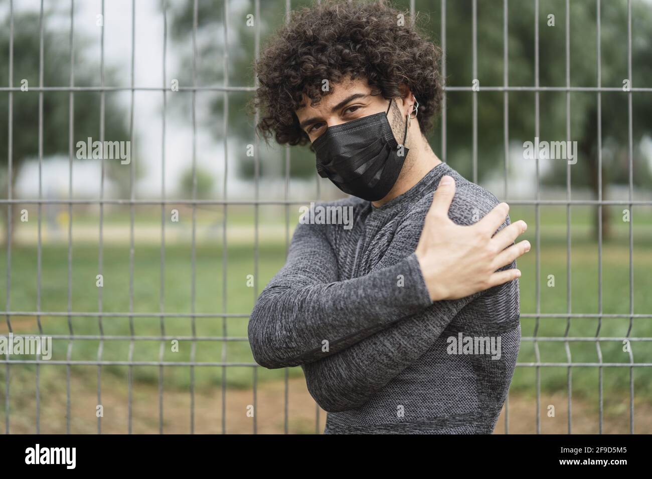 Enfoque poco profundo de un hombre de pelo rizado con una máscara de vestir  Ropa deportiva en un parque en España Fotografía de stock - Alamy